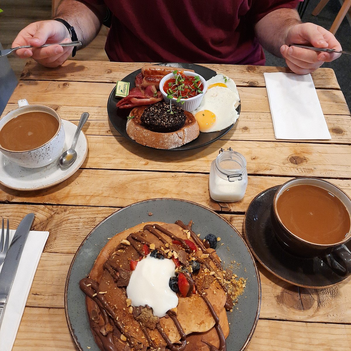 Breakfast plates and coffee spread across a timber table inside Railway St.