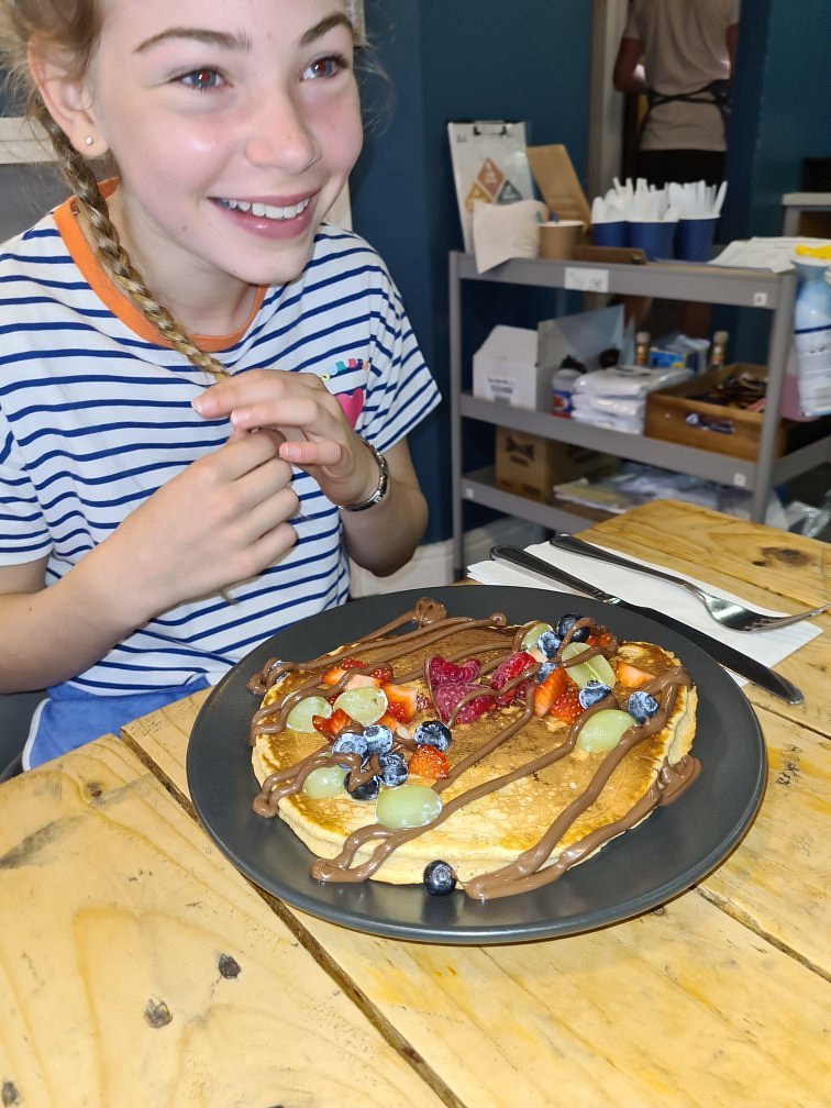 Customer smiling over a pancake plate inside the cafe